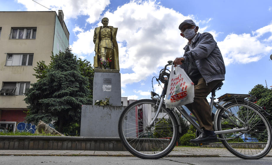 A man rides a bicycle near the monument to Josip Broz Tito in Skopje