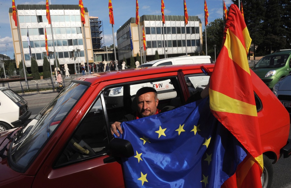 Човек држи знаме на Европската Унија и македонско знаме пред Владата, по извештајот на Европската комисија кој препорачува почеток на пристапните преговори за Македонија / 14 октомври 2009 година / EPA/GEORGI LICOVSKI